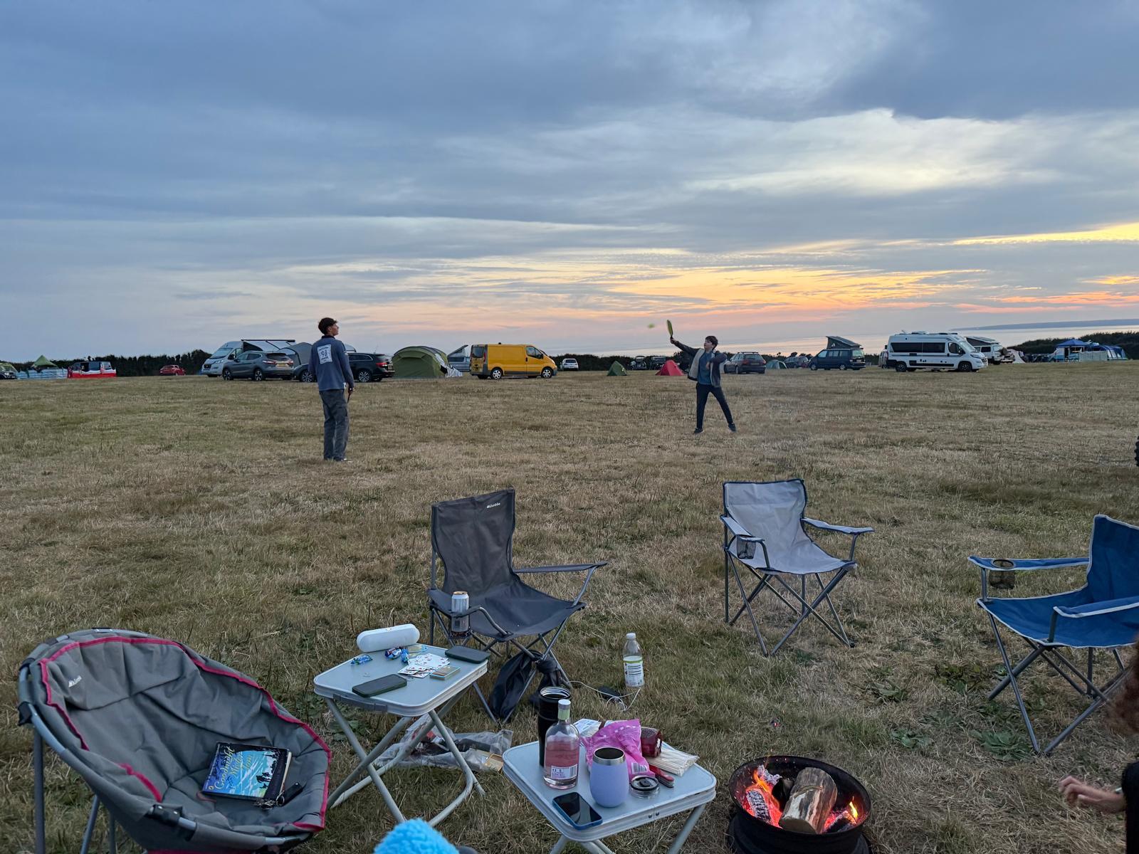 Camp chairs set out at dusk with tents in the background